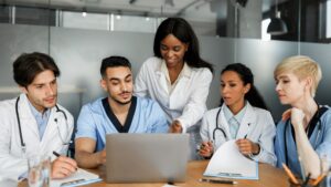 clinicians collaborating and looking at medical software on a laptop screen